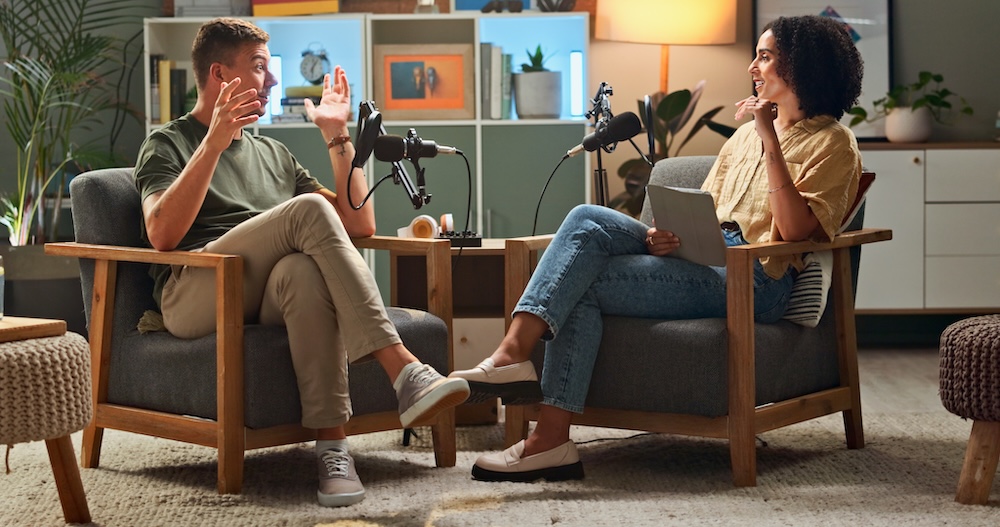 Man, woman and podcast with mic, discussion and home studio with smile for live stream on social media. People, happy and interview with conversation, story or gossip for internet culture on web show.