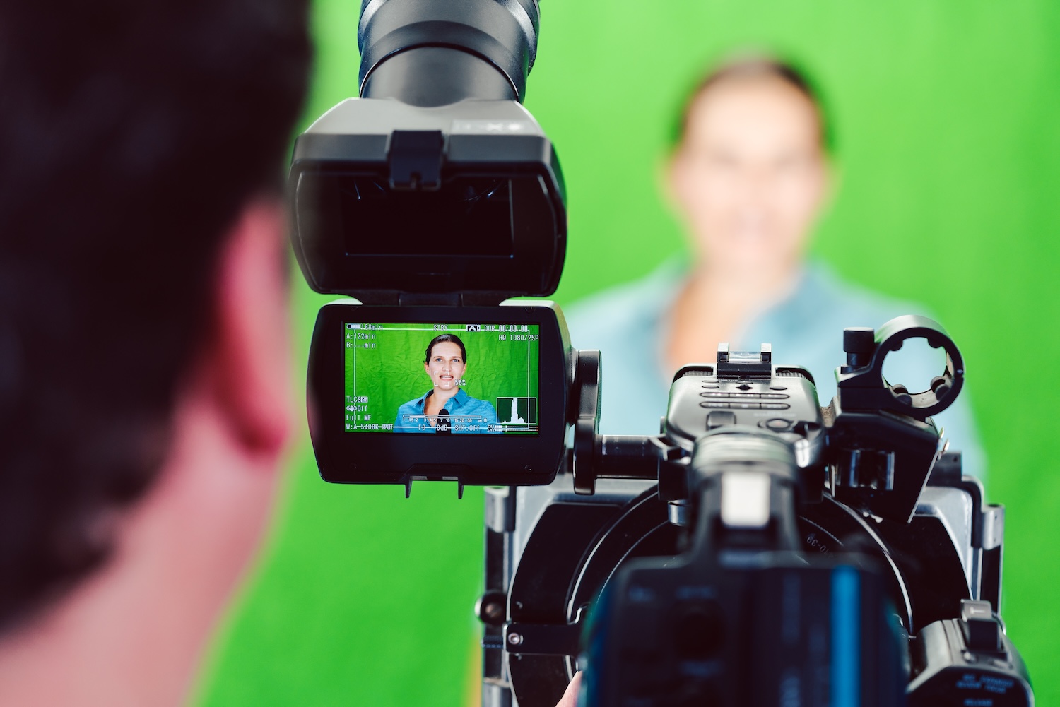 Camera pointed at a news woman or reporter in green room studio, shot at the control monitor